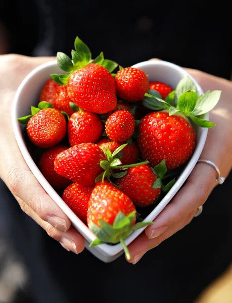 草莓心形状碗的手里 — 图库照片