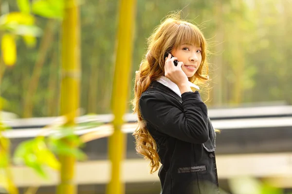 Business woman talk phone beside trees — стоковое фото