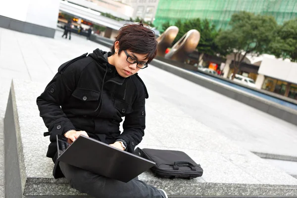 Ásia homem usando computador ao ar livre — Fotografia de Stock