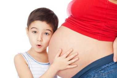 Surprised boy holding mother's belly with hands and listening clipart