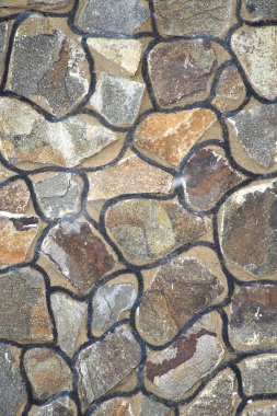 Wall from multi-coloured stones of the various form fastened by clay clipart