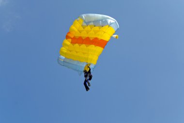 The person jumps with a parachute against the blue sky clipart