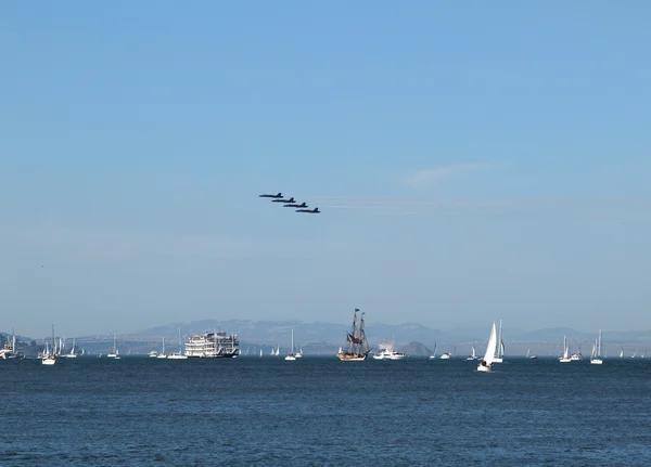 Vier blaue engel fliegen an einer flotte von booten in der bucht von san francisco vorbei — Stockfoto