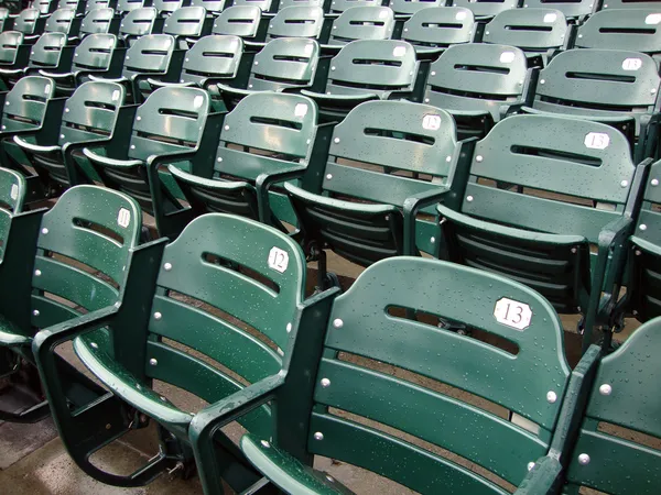 Rows of empty wet green stadium seats, seats number 13, 12, 11 — Stok fotoğraf