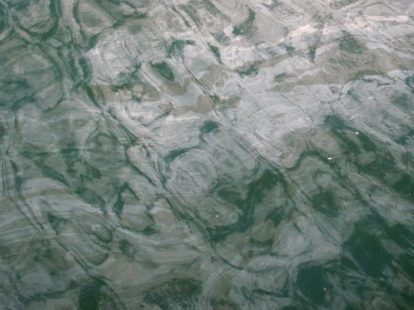 Slick of oil on top of green creek water — Stock Photo, Image