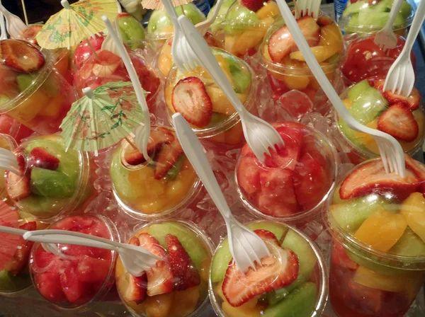 Πλαστικά ποτήρια φρούτα με πιρούνια τοποθετούνται πάνω στην οθόνη — Φωτογραφία Αρχείου