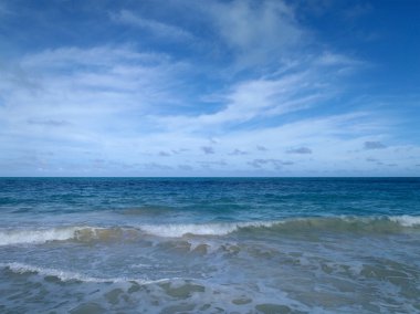 Waimanalo Beach Hawaii dramatik mavi bulutlu gökyüzü ile kıyıya doğru dalgalar gürültüyle çarpmak