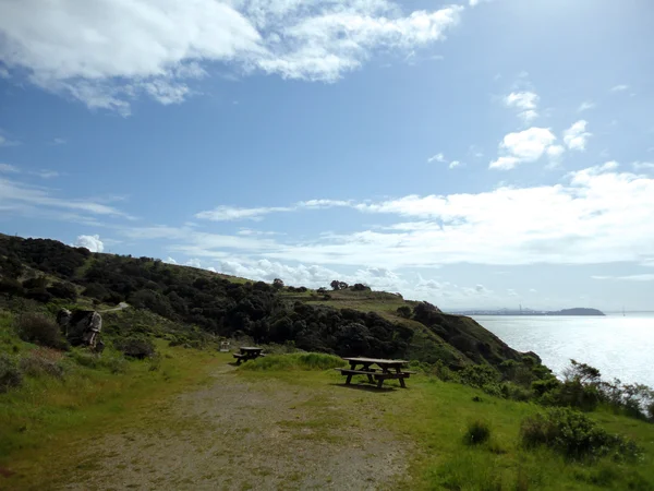 Mesas de picnic en la isla Ángel con Bay Bridge en la distancia — Foto de Stock