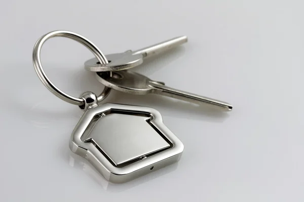 Due chiavi d'argento con figura casa in metallo — Foto Stock