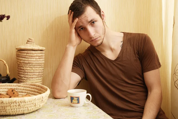 Young guy with tea and rusk in the kitchen — Stock Photo, Image
