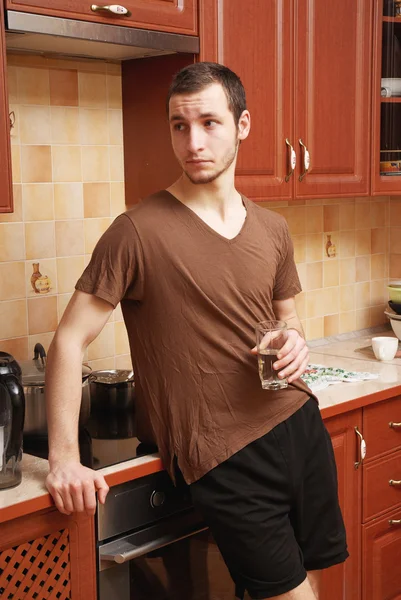 Guy in the kitchen with glass of water — Stock Photo, Image
