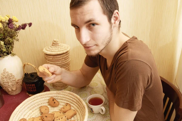 Young guy with tea and rusk in the kitchen — Stock Photo, Image