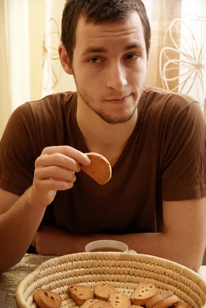 Jonge kerel met thee en rusk in de keuken — Stockfoto