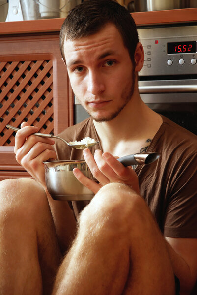 Guy with pot of rice in the kitchen