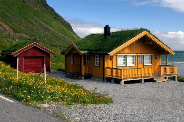 Casa de madeira amarela com telhado de grama Imagens Royalty-Free