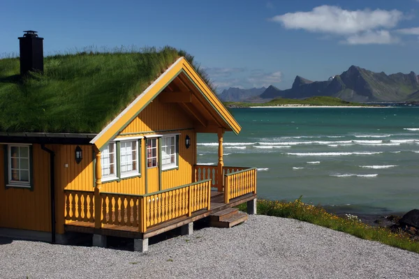 Casa in legno giallo con tetto in erba Immagine Stock
