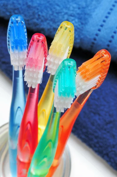 Cinco Escovas Dentes Multicoloridas Copo Água Azul Frente Toalha Azul — Fotografia de Stock