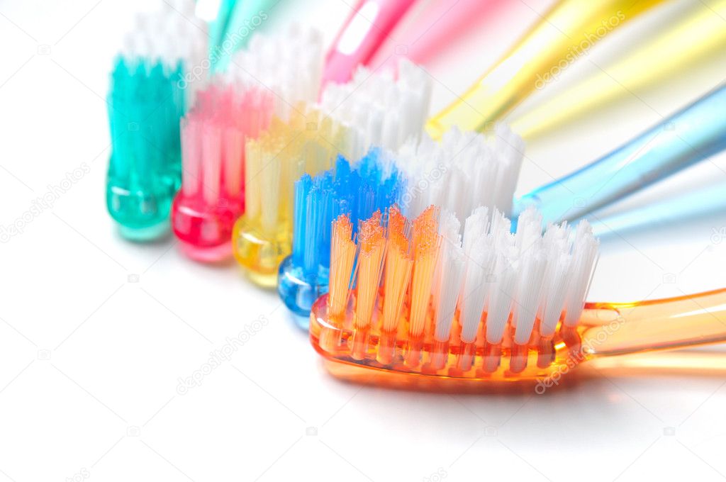 Five multicolored toothbrushes over white background