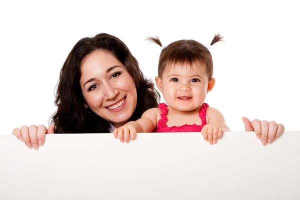 Moeder en baby dochter houden wit bord — Stockfoto