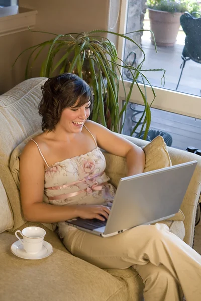 Женщина на диване болтает на ноутбуке — стоковое фото