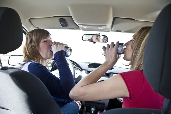 两个女人在车里喝酒 免版税图库图片