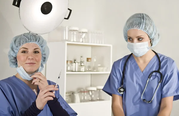 护士和医生在手术与注射器 图库照片