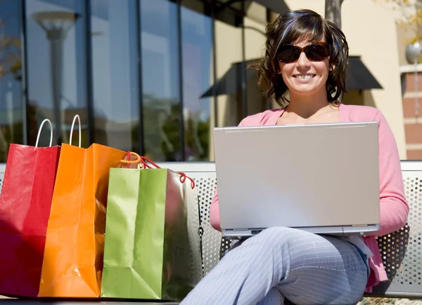 Woman with shopping bags and laptop — Stock Photo, Image