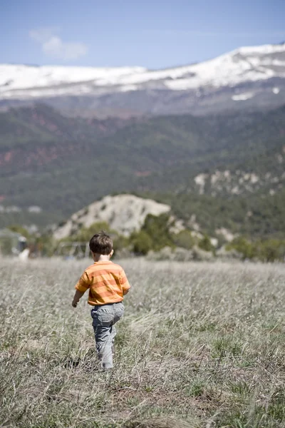 Jovem rapaz caminhando em um prado de montanha — Fotografia de Stock