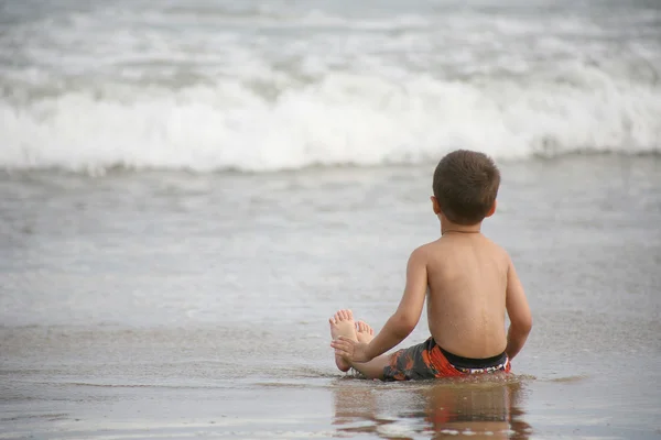 Niño jugando en la playa y las olas — Foto de Stock