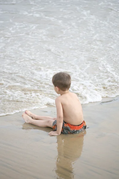 Jongen speelt op het strand en de golven — Stockfoto