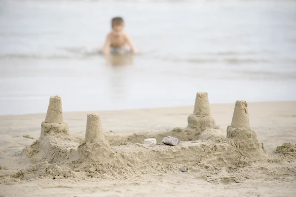 Мальчик играет на пляже и волны — стоковое фото