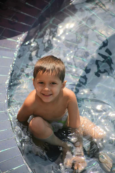 Мальчик сидит в бассейне и улыбается. — стоковое фото