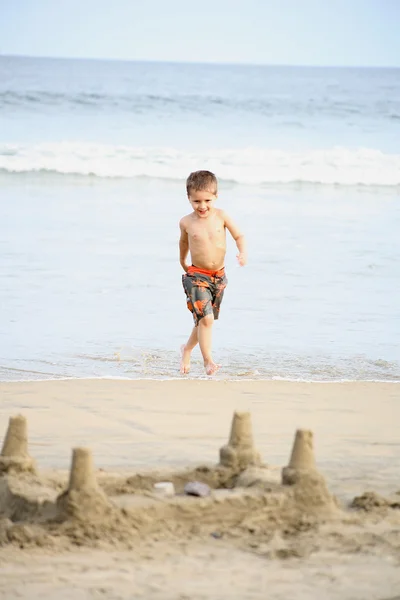 小男孩玩的沙滩和海浪 — 图库照片