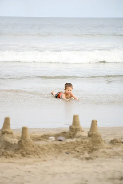 Młody chłopak gra na plaży i fale — Zdjęcie stockowe