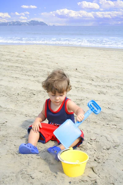Mały chłopiec bawi się w piasku na plaży — Zdjęcie stockowe