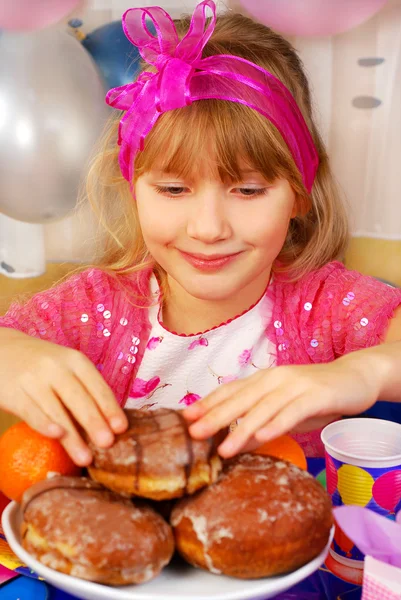在晚会期间吃甜甜圈的年轻女孩 — 图库照片