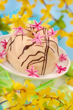 Almond ring cake poured white and dark chocolate on easter table clipart