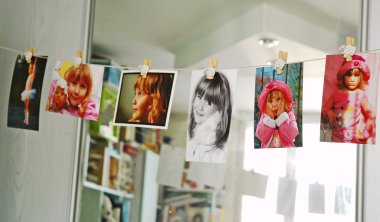 Child photographs hanging on a clothesline in room clipart