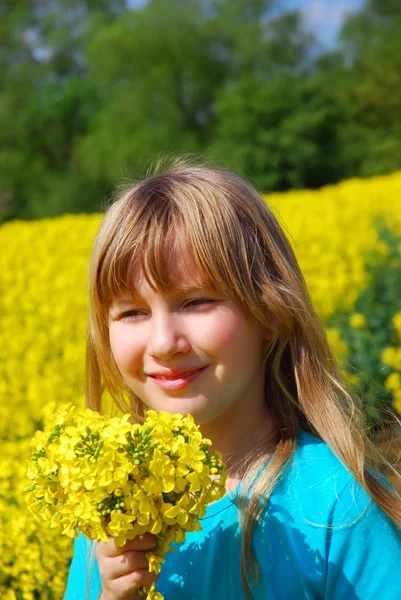 黄色の花の束との春菜の花畑を歩いて若い女の子 — ストック写真