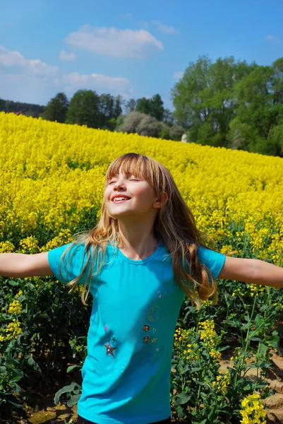 Happy young girl in rape field — Stock Photo, Image