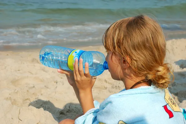 Young girl drinking water on the beach — Stock Photo, Image