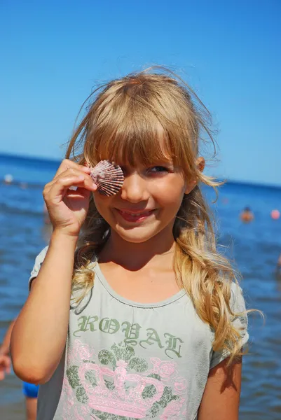 Young girl on beach with shell — Stock Photo, Image