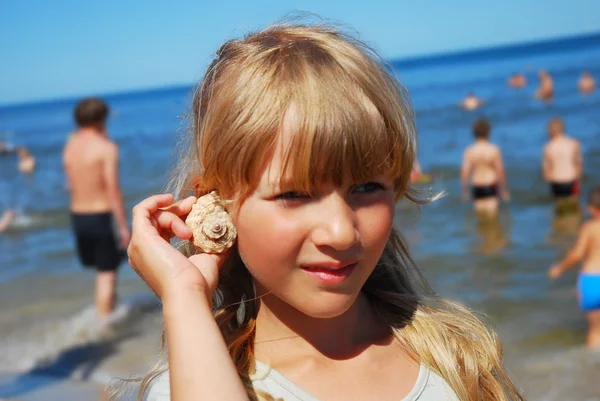 Young girl on beach with shell — Stock Photo, Image