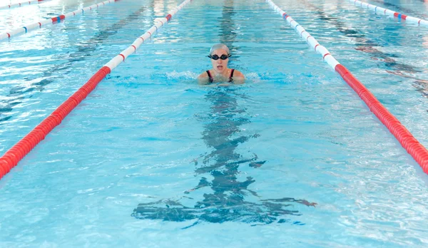 Giovane donna nuotare sulla piscina coperta. stile breastroke . — Foto Stock