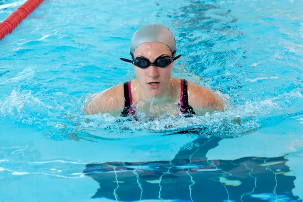 Giovane donna nuotare sulla piscina coperta primo piano. stile breastroke . — Foto Stock