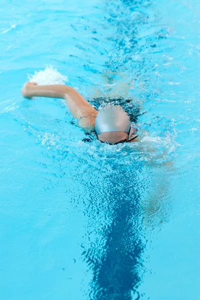 Giovane donna nuotare sulla piscina coperta. modalità stile libero . — Foto Stock