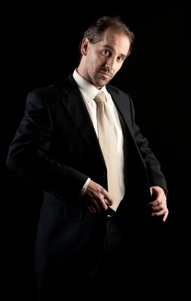 Businessman buttoning jacket, getting dressed, on dark background — Stock Photo, Image