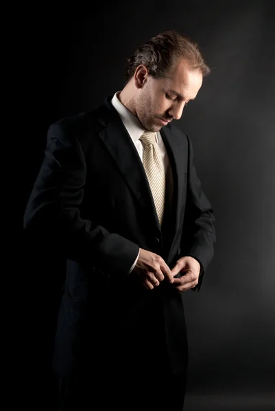Businessman abbottonatura giacca, vestirsi, su sfondo scuro — Foto Stock