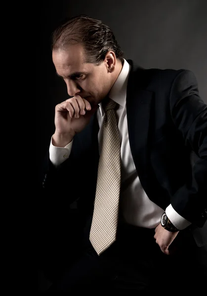 Adulto uomo d'affari serio pensiero seduto su sfondo scuro — Foto Stock