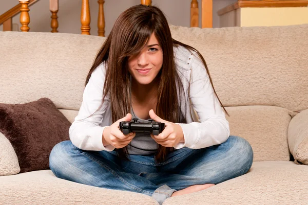 stock image Young female concentrating playing videogames on sofa at home